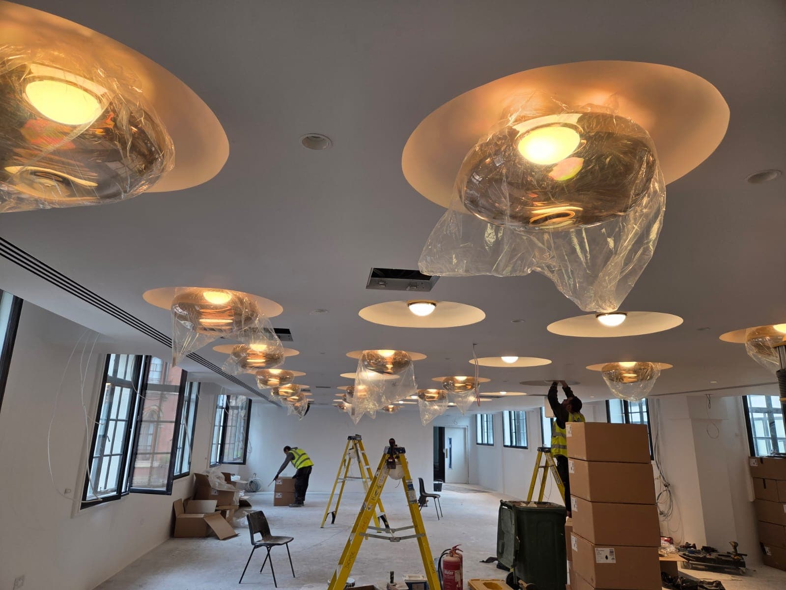Prime Electric team installing commercial ceiling lighting in a modern office space